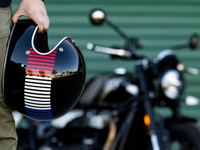 A rider casually holds his Biltwell Gringo Helmet by his side before getting on his Harley-Davidson